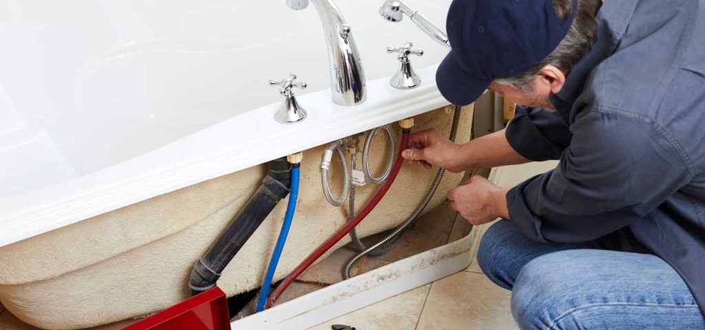 Plumber working on bathtub plumbing.