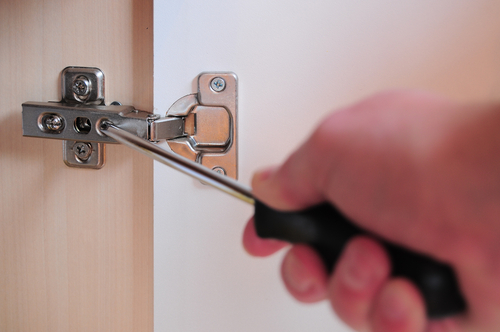 A man repairing the door hinge using instrument