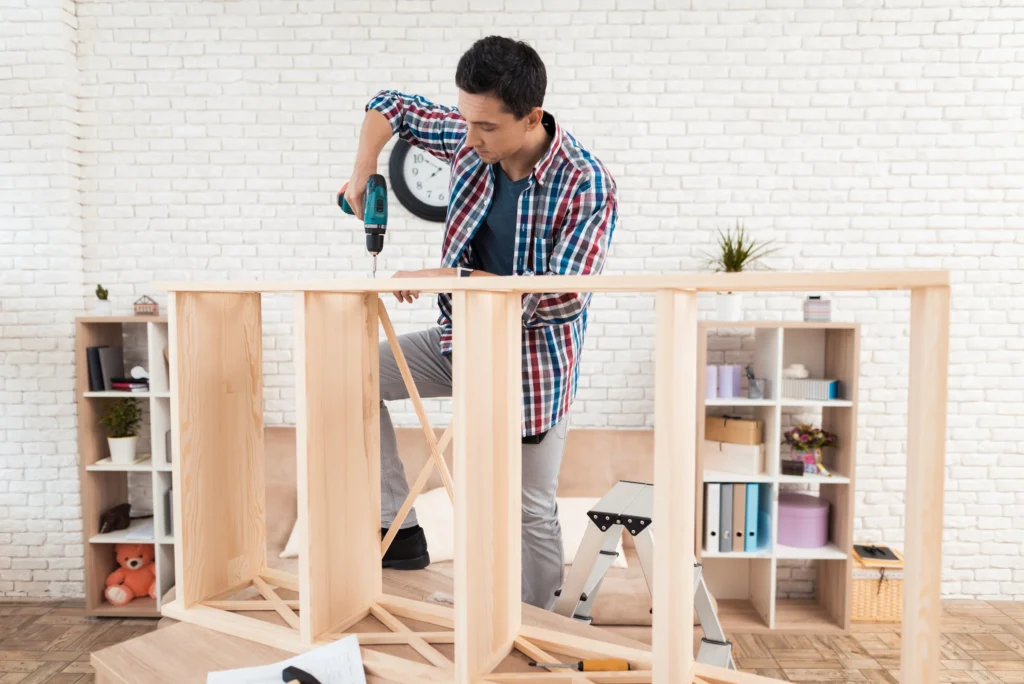 Man assembling wooden furniture with a drill.