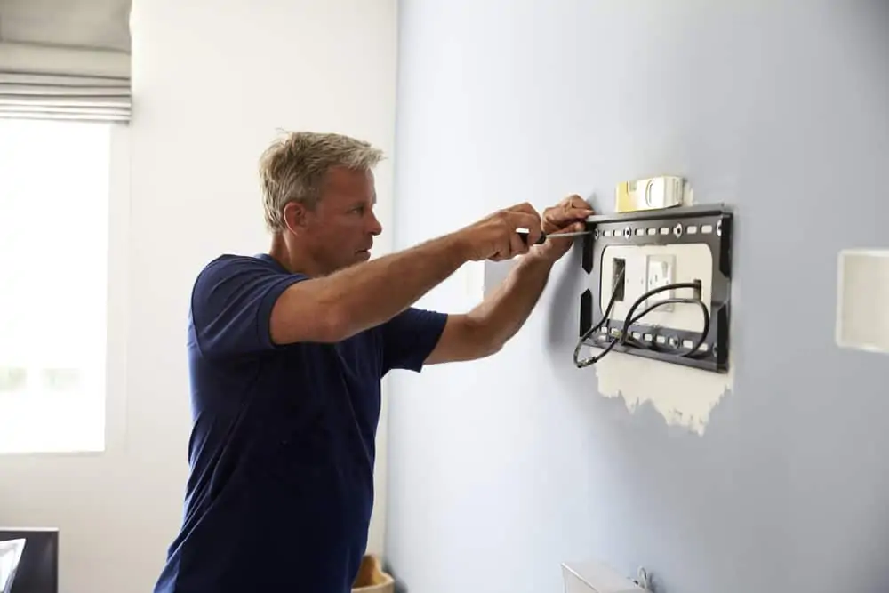 Man mounting a TV bracket on a wall.