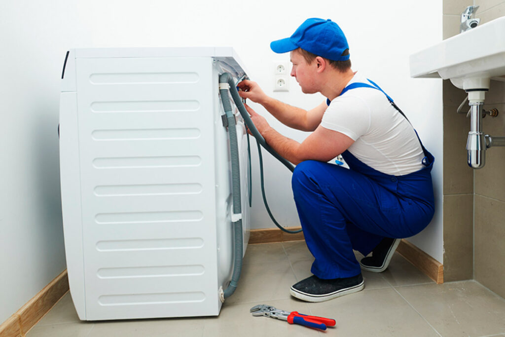 Technician working on washing machine hoses.