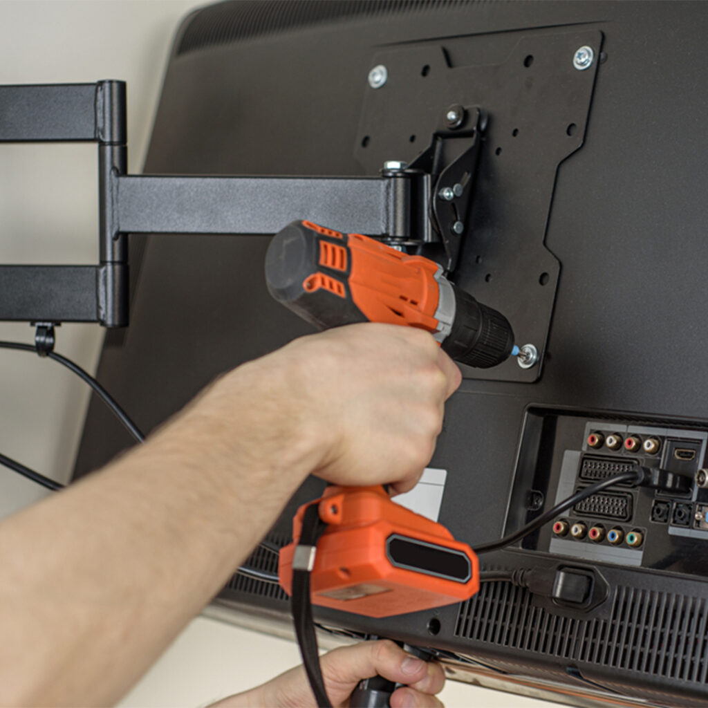 Person drilling TV onto wall mount.