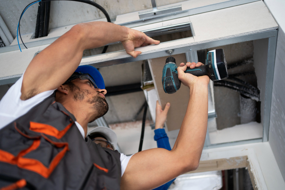 Two construction workers installing a drywall ceiling.