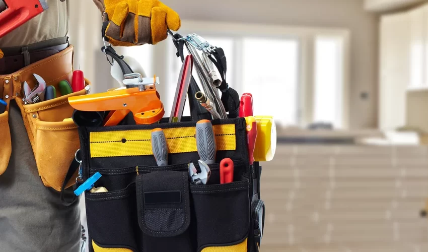 Hand holding a tool bag with various tools.