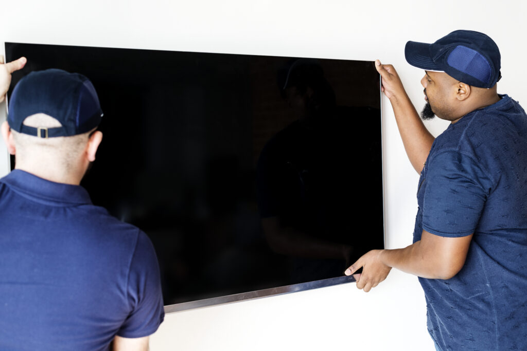 Two men mounting a large TV on a wall.
