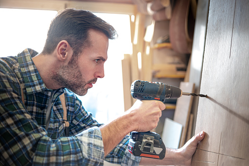 Man drilling a hole in wood.