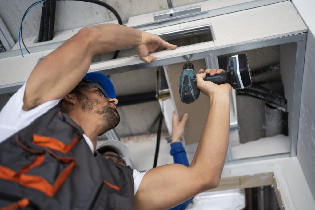 Worker drilling ceiling board.