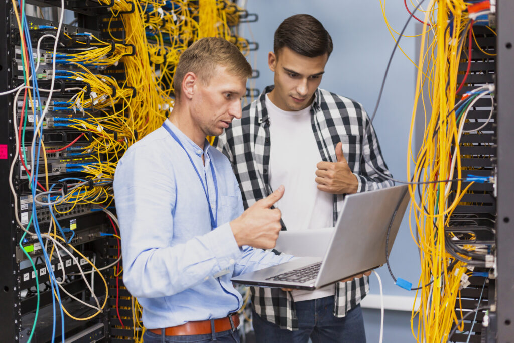Two technicians with a laptop in a server room.